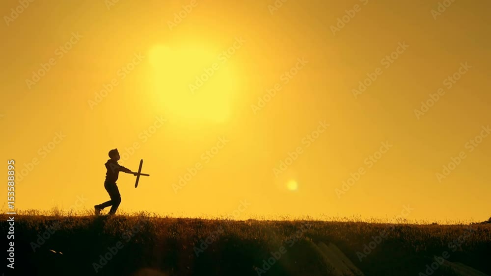 Boy playing with airplane model against orange sunset background Boy playing with airplane model against orange sunset background