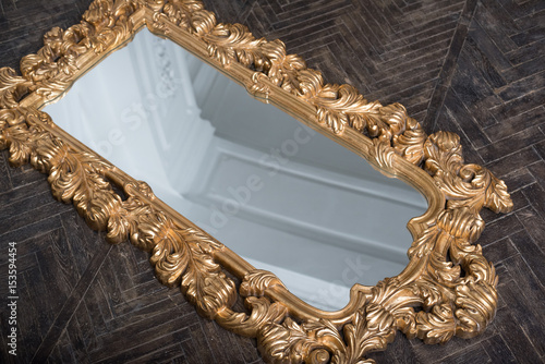 Antic gilded mirror on the wooden floor
