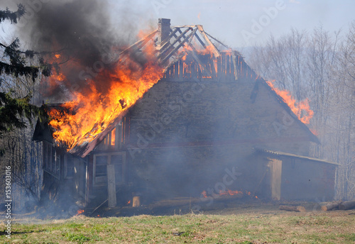 Burning wooden house. Burning fire flame on wooden house roof. Building covered by flame.