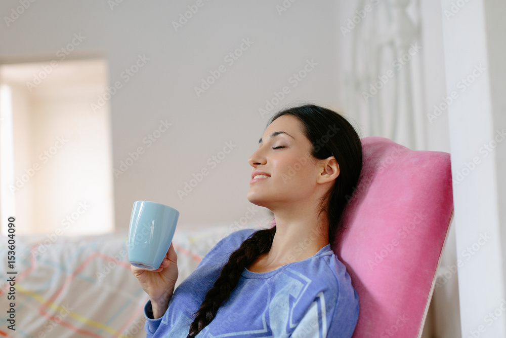Young woman sitting on chair drinking from mag in her bedroom Young woman sitting on chair drinking from mag in her bedroom