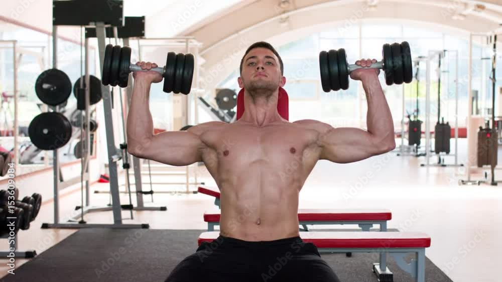 Man working his arms at the gym. He lifting the dumbbells. Naked torso. Man working his arms at the gym. He lifting the dumbbells. Naked torso.