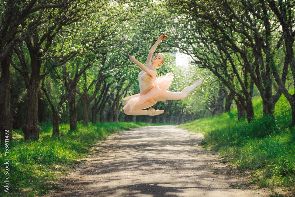 Ballerina dancing outdoors and jumping high into the air