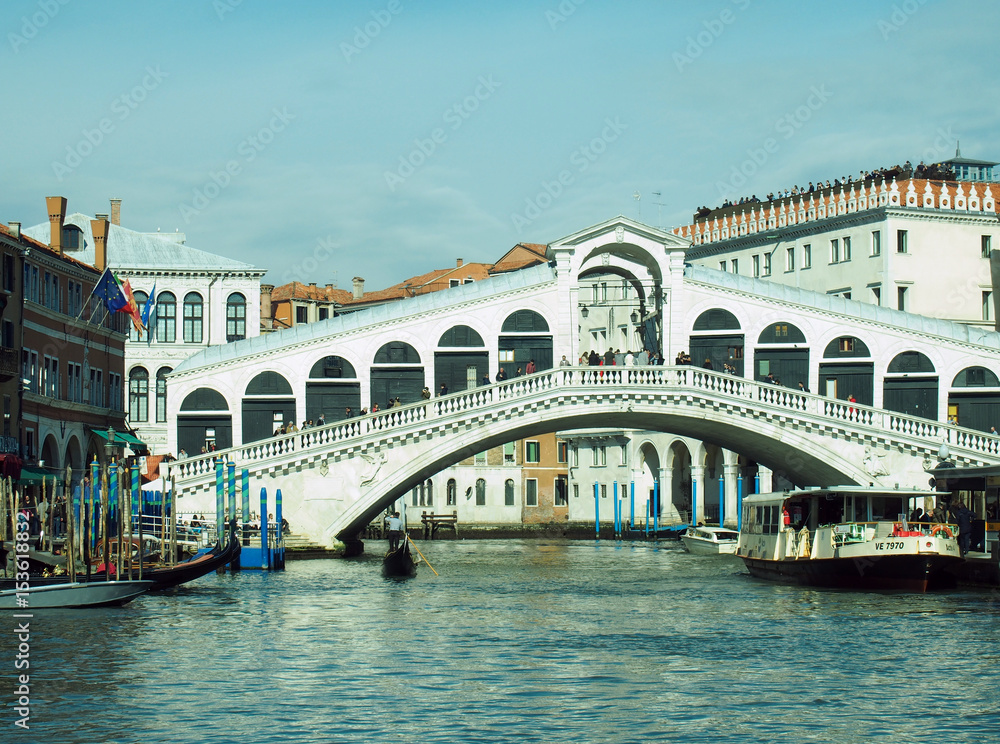 The rialto bridge in venice with boats and blue sky