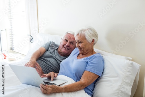 Senior couple using laptop in the bedroom