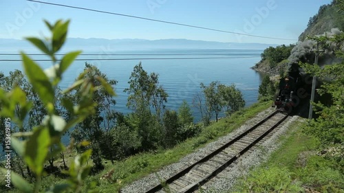 Historic steam train passes through the mountains. Steam locomotive moving through the mountains. TRANS-Siberian railway, lake Baikal. Vintage railroad along the lake shore. Russia Siberia.
