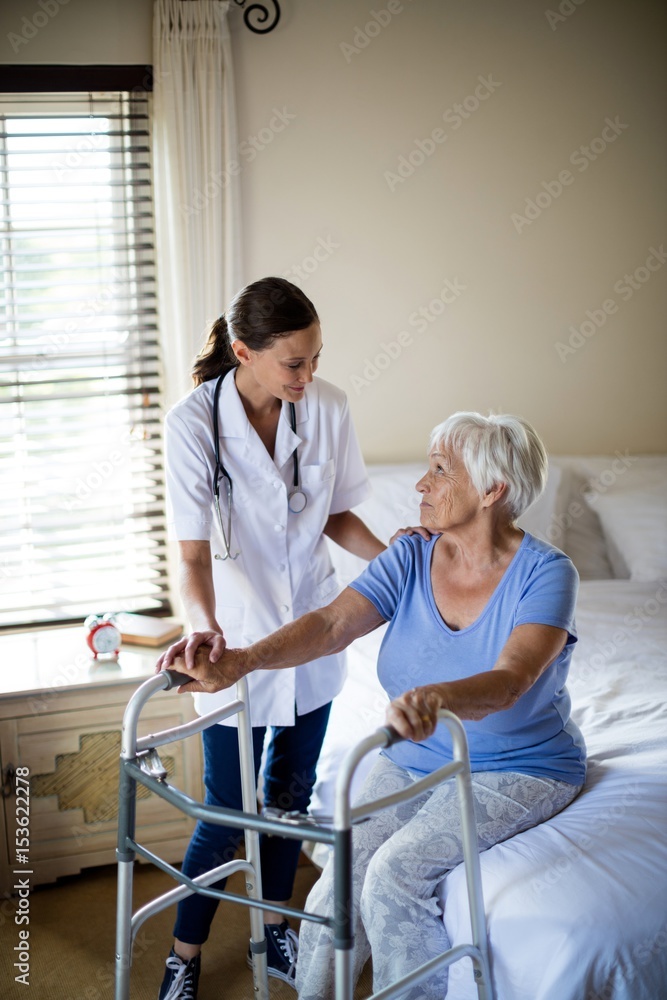 Female doctor helping senior woman to walk with a walker Female doctor helping senior woman to walk with a walker