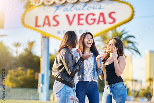 group of girls on vacation having fun together in front of welcome to las vegas sign