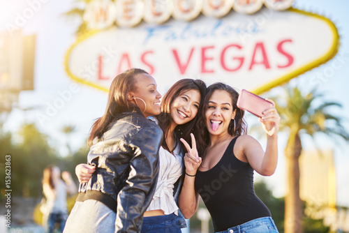 diverse all girl group of friends having fun taking selfies in front of welcome to las vegas sign