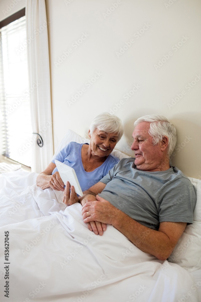 Senior couple using digital tablet in the bedroom Senior couple using digital tablet in the bedroom