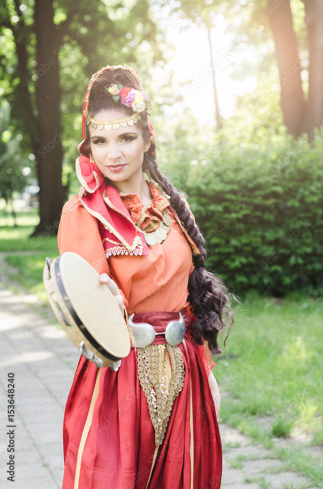 gypsy in folk costume dances with tambourine outdoors