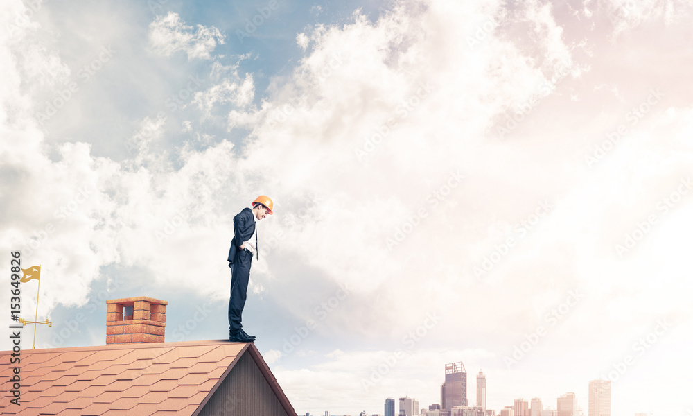 Businessman looking down from roof and modern cityscape at backg Businessman looking down from roof and modern cityscape at backg