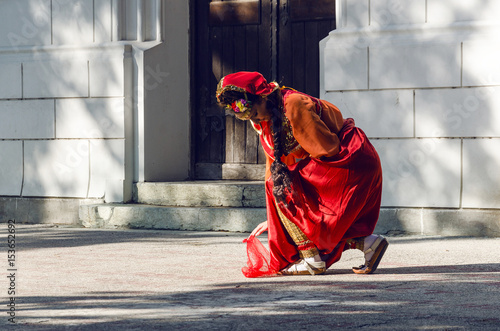 girl in Turkish costume dancing with a scarf in front of the large doors