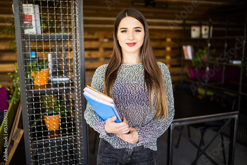 Freelance developer or designer with notebooks and papers standing at office room photo