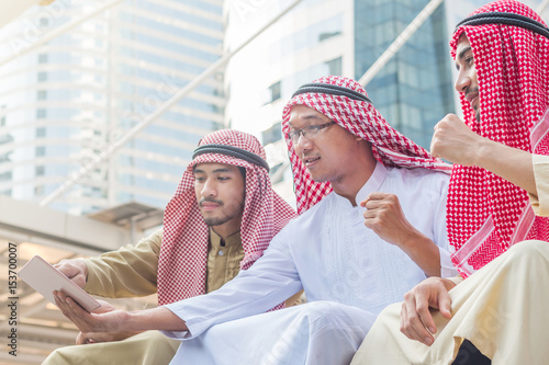 The group of arabian businessman smiling and watching tablet