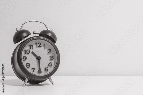 Closeup alarm clock for decorate show half past ten o'clock or 10:30 a.m.on white wood desk and cream wallpaper textured background in black and white tone with copy space