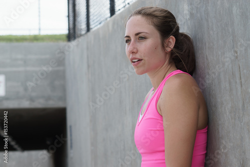 Young woman resting on wall after exercising