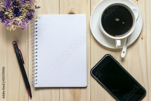Flat lay desk with coffee, notebook, smartphone and flowers