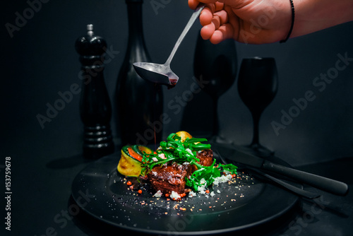 steak in red wine with grilled vegetables and wine on black background