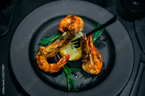 fried shrimps grill with lemon on black plate
