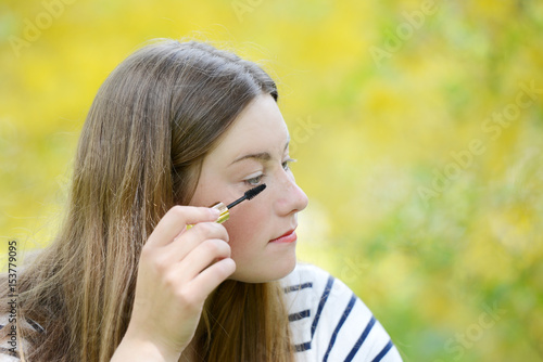 Make-up and cosmetics concept. Beautiful young woman doing her makeup eyelashes black mascara.