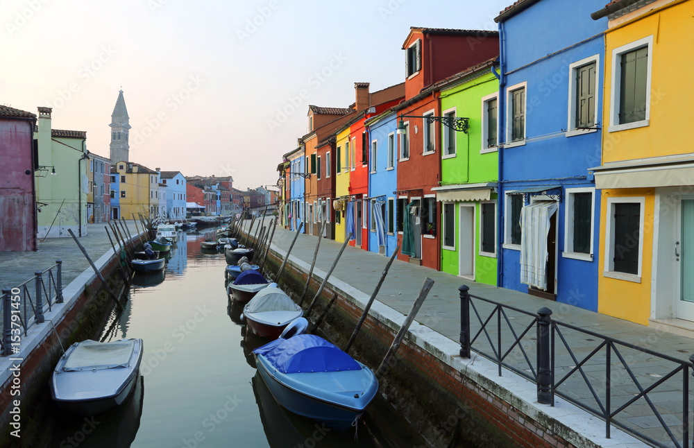 Boats moored in the waterway near the colorful houses of the island of Burano in Italy