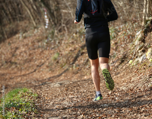 Leg of athlete runner from behind during racing on the mountain trail