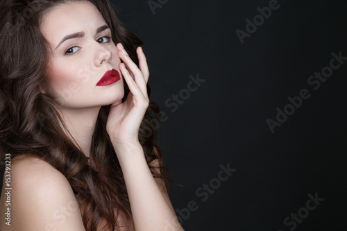 Blissfully beautiful. Studio shot of a beautiful confident-looking female posing with her hand to her face on black background copyspace on the side.