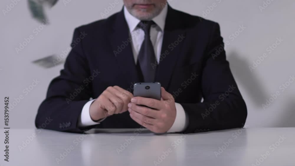 Dollars falling on adult man in expensive suit browsing on smartphone, fortune Dollars falling on adult man in expensive suit browsing on smartphone, fortune