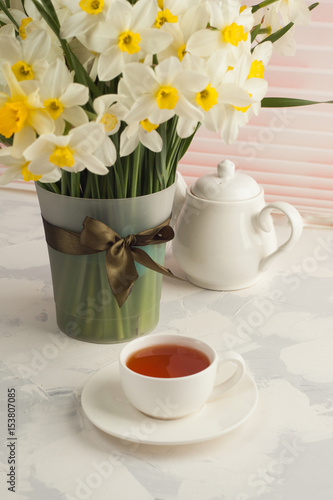 Fototapeta Naklejka Na Ścianę i Meble -  Breakfast still life, Cup of tea teapot, a bouquet of yellow flowers - daffodils and narcissus. Spring flowers background, vertical