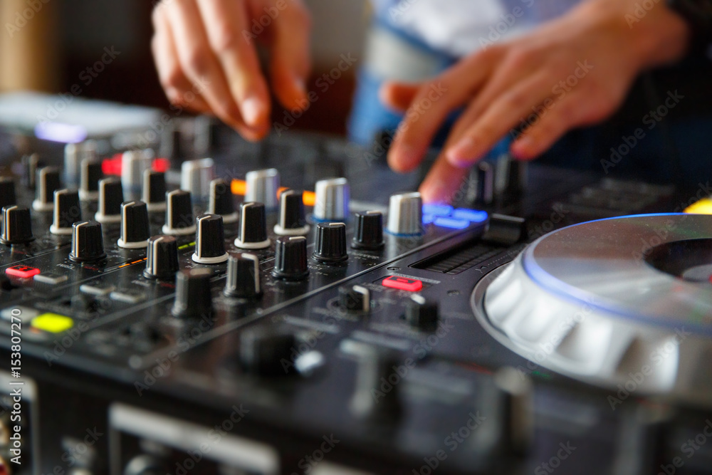 The hands of a professional DJ set up the dj's panel with a many buttons and control knobs to play music