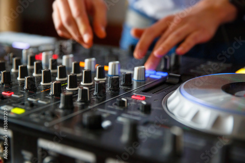 The hands of a professional DJ set up the dj's panel with a many buttons and control knobs to play music © Daria