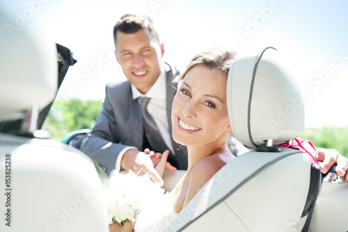 Portrait of beautiful smiling bride sitting in convertible car
