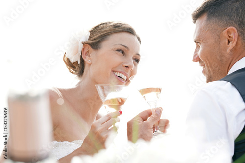 Happy bride and groom celebrating wedding with champagne