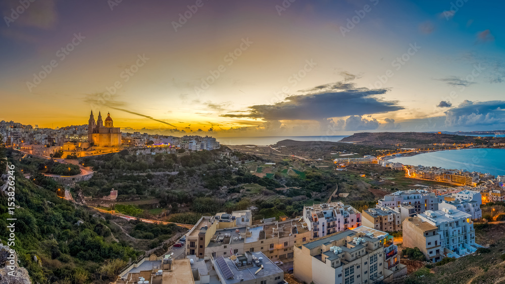 Il-Mellieha, Malta - Beautiful panoramic skyline view of Mellieha town at sunset with Paris Church and Mellieha beach at background with blue sky and clouds