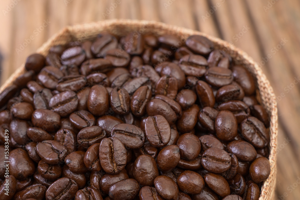 Fototapeta premium Sack of coffee beans on wood background
