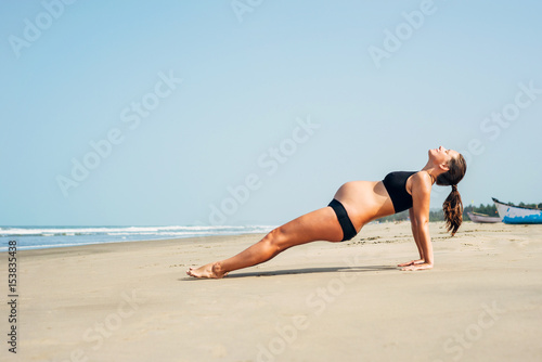 Pregnant woman on the beach doing yoga. Pregnant woman doing purvattanasana. Pregnant woman doing workout near the the sea.