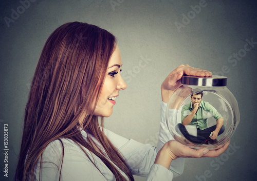 Photos Woman holding a glass jar with imprisoned man in it