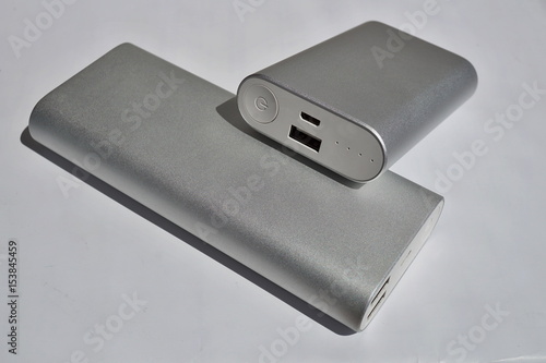 Macro detail of two silver power banks (external batteries) in modern simple design on white surface as a symbol of mobile energetic power source 