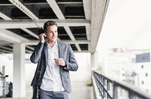 Wallpaper Mural Young businessman using smartphone, walking on parking level Torontodigital.ca