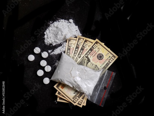 Cocaine drug powder bag, pile and line, pills and dollar money bills on black background