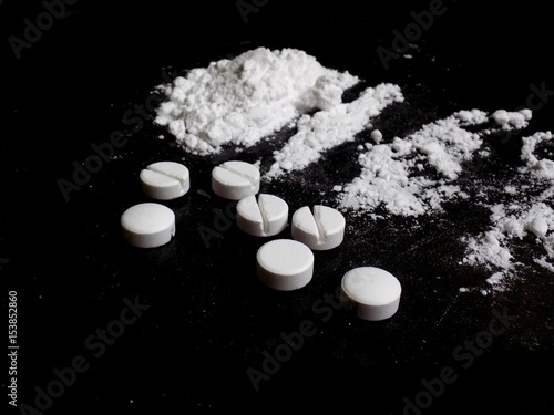 Cocaine drug powder pile and lines and pills on black background