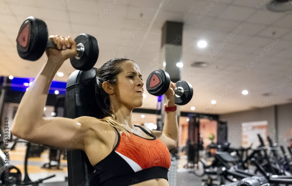 Woman lifting dumbbells in gym Woman lifting dumbbells in gym