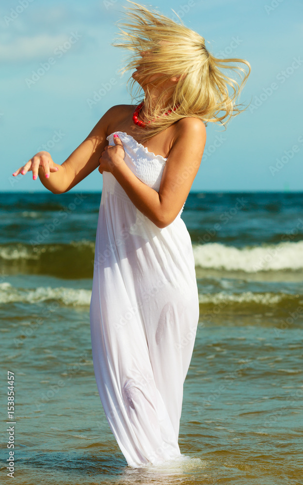 Blonde woman wearing dress walking in water Blonde woman wearing dress walking in water