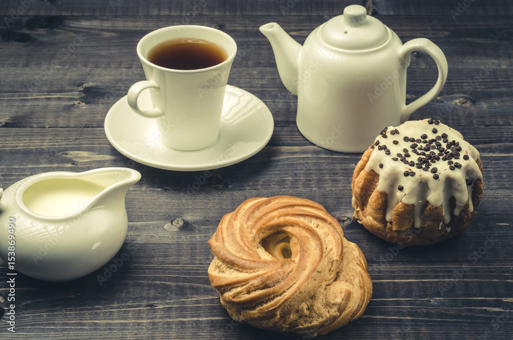 breakfast with white ware and a roll/cup, coffee, creamer, teapot, sweets on a dark background