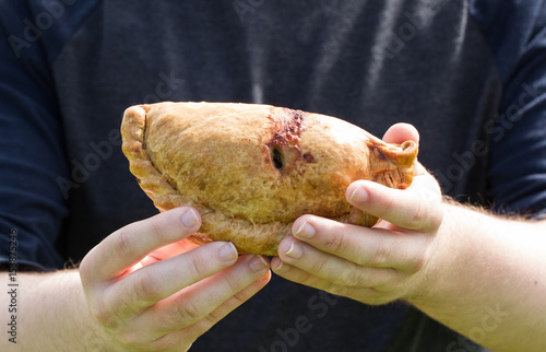 Φωτογραφία A boy or man holding up a traditional Cornish pasty in his hands in a mid shot to the camera