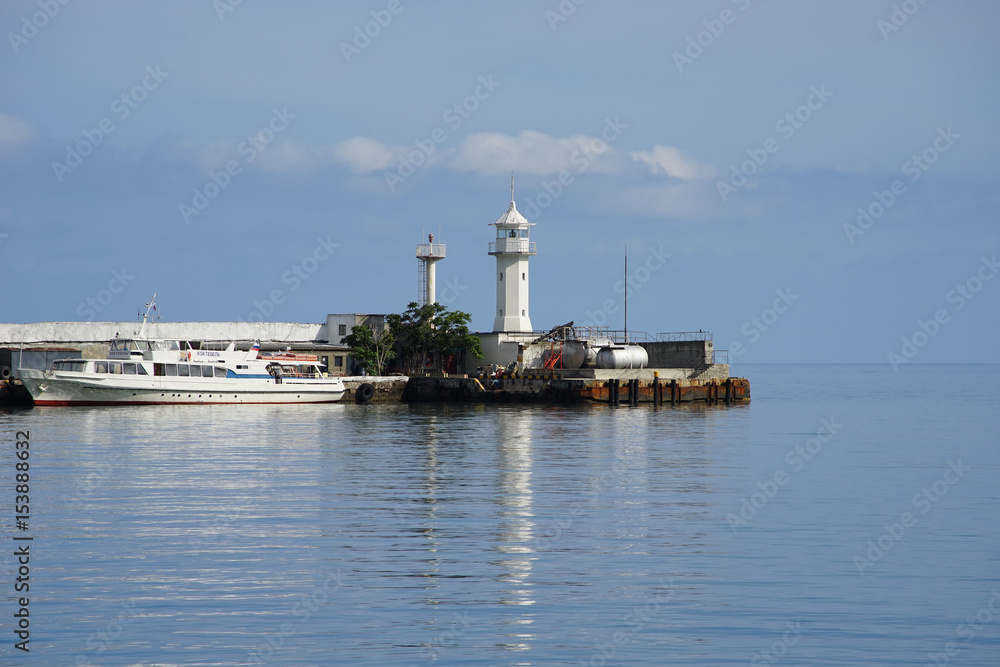 marine landscape with a white lighthouse on a background of calm sea