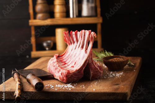 Raw rack of lamb with spices on a cutting board