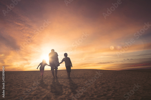 Father and children walking on the sand