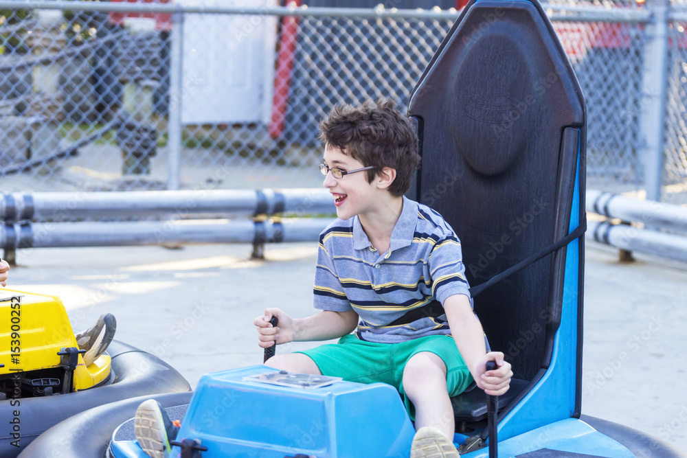 Young boy steering bumper car at amusement park in summer, happy Young boy steering bumper car at amusement park in summer, happy