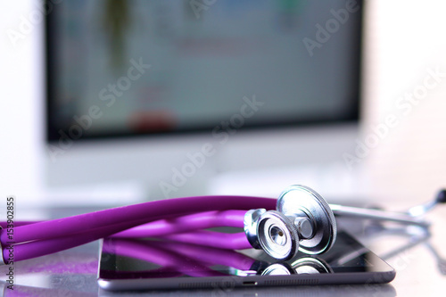 Tablet computer with a stethoscope lie on a table